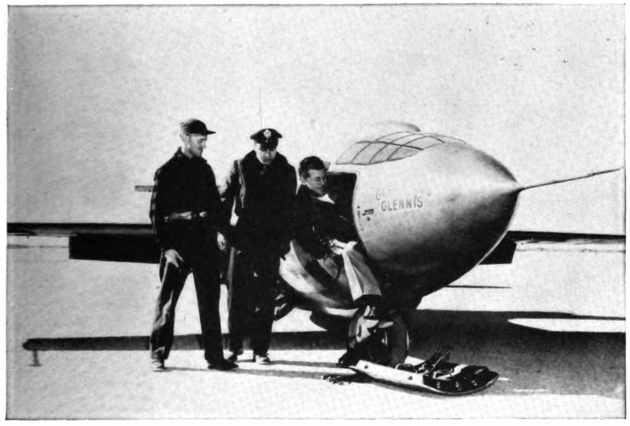 A man crawling out of a plane with two men standing beside it