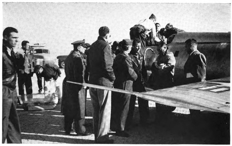 a ground of men gathered around a plane