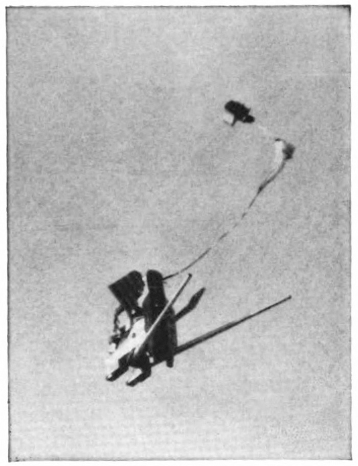 A portion of a plane with an unopened parachute behind it