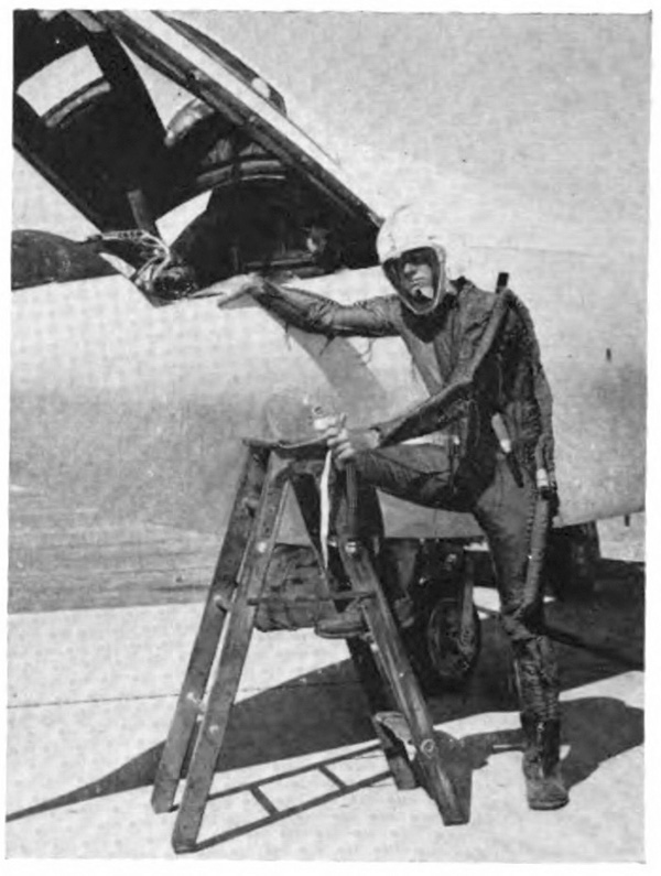 A man in a suit with his foot on a ladder, standing next to a plane